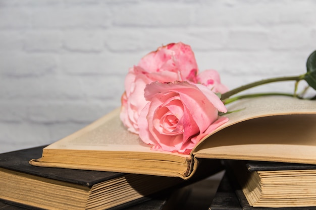 Un bouquet di rose rosa e libri su legno rustico