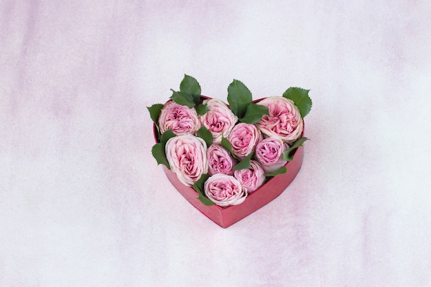 un bouquet di rose rosa in confezione regalo a forma di cuore