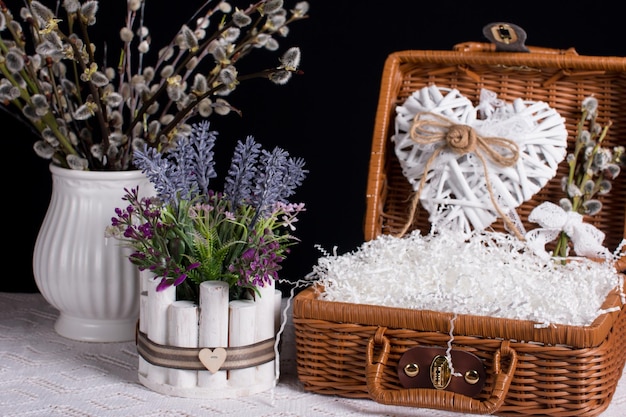 Un bouquet di salice in un vaso su sfondo nero Valigie di vimini con fiori e un bouquet di lavanda Provenza