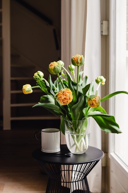 Un bouquet di tulipani arancioni freschi e una tazza bianca