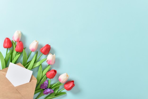 Un bouquet di tulipani con una cartolina su sfondo blu Giornata internazionale della donna 8 marzo Festa della mamma Pasqua compleanno Spazio copia Vista dall'alto piatta