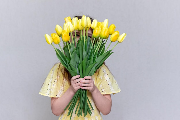Un bouquet di tulipani gialli copre il viso delle ragazze.