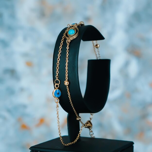 Un bracciale nero e oro con una pietra blu e una catena d'oro.