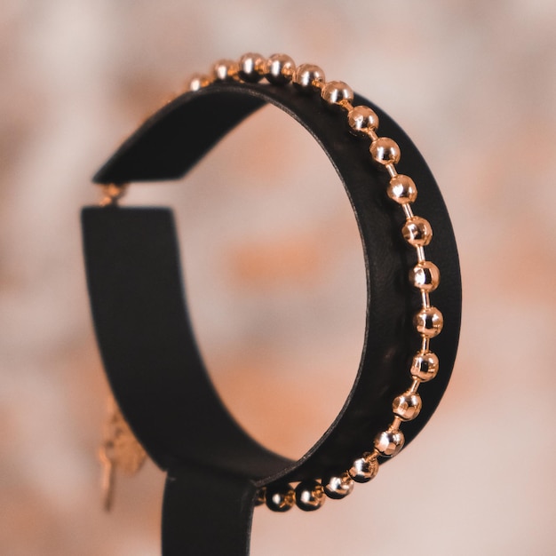 Un braccialetto di pelle nera con perline d'oro e una chiave.