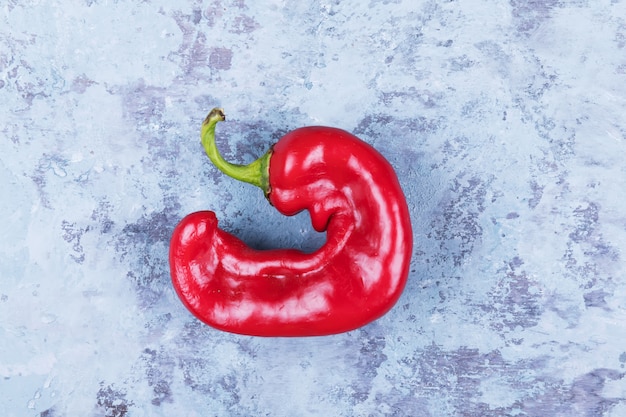 Un brutto peperoncino rosso alla moda su un grunge blu, stile minimal, cibo creativo