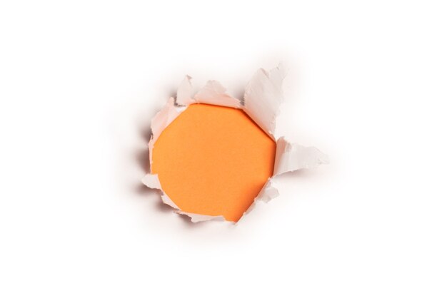 Un buco in una carta bianca su uno sfondo arancione, copia dello spazio.