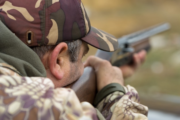 Un cacciatore in mimetica al poligono di tiro calibra l'arma. Un uomo spara ai bersagli.