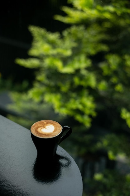 Un caffè caldo con forma di cuore artistico su un tavolo nero in una caffetteria.