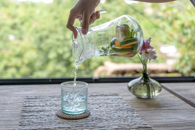 Un cameriere in un ristorante versa l'acqua di frutta da una caraffa in un bicchiere