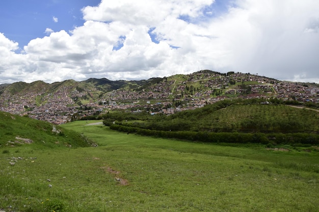 Un campo con erba verde davanti alle rovine Inca Saqsaywaman vicino a Cusco