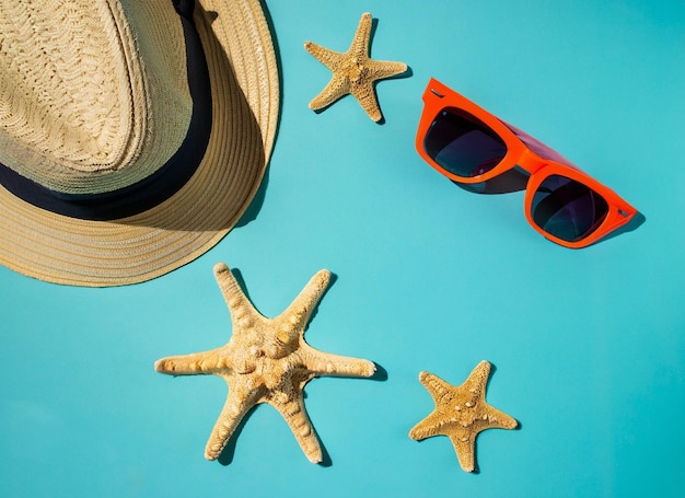 Un cappello e una stella marina sono su uno sfondo blu con un cappello e occhiali da sole.