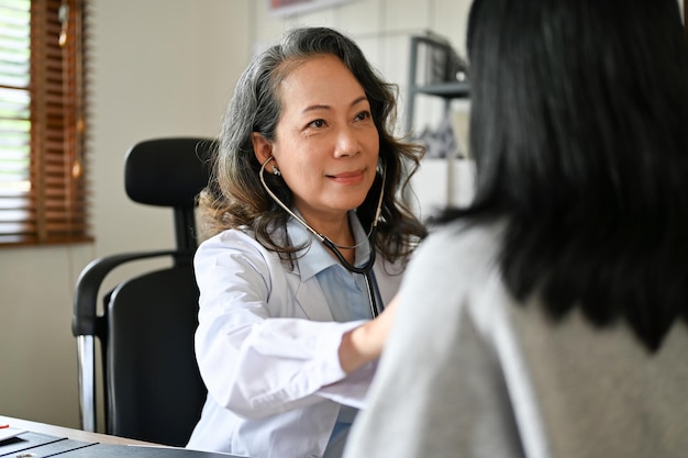 Un cardiologo medico femminile asiatico senior professionista controlla utilizzando uno stetoscopio