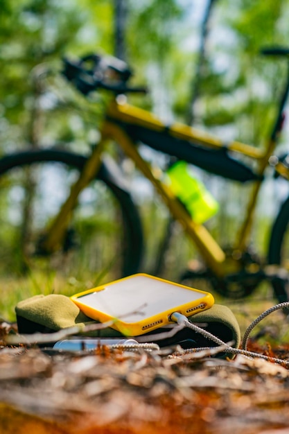 Un caricabatterie portatile carica lo smartphone Power Bank con cavo sullo sfondo della foresta e della bicicletta