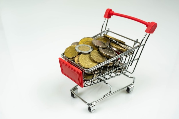 Un carrello del supermercato pieno di monete Sullo sfondo bianco semplice Simboleggia gli investimenti finanziari e il mercato dei cambi