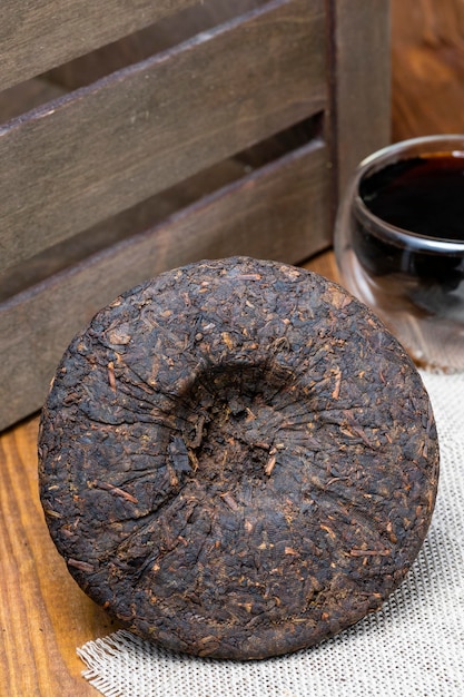 Un cerchio di tè puerh nero cinese compresso su uno sfondo di legno
