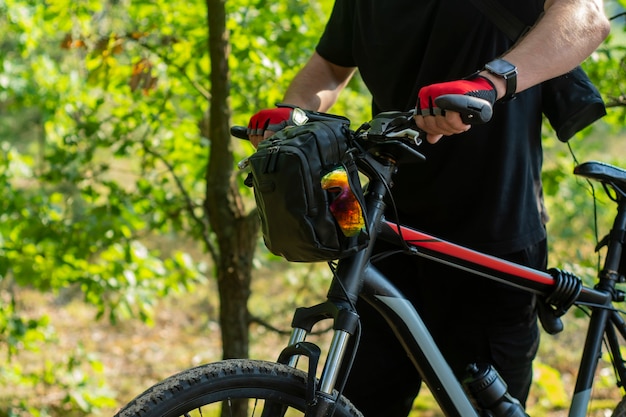 Un ciclista in guanti vicino a una mountain bike con una borsa sul manubrio.