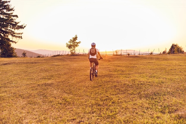 Un ciclista va in bicicletta su strade forestali al tramonto