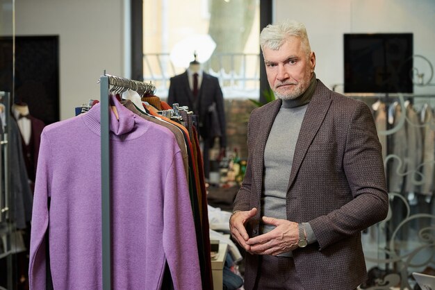 Un cliente maschio con la barba indossa un abito in una boutique.