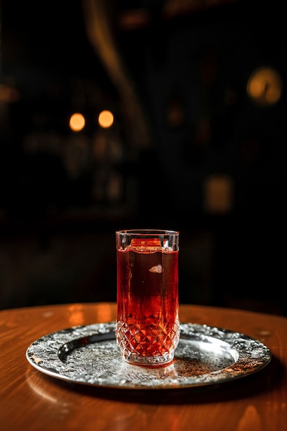 Un cocktail long drink con ghiaccio in un bicchiere highball vintage su un vassoio d'argento