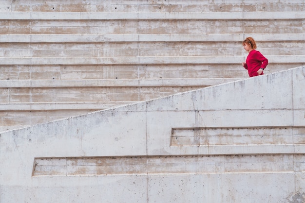 Un colpo generale da dietro di una donna che corre giù per le scale all'aperto