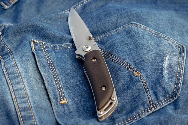 Un coltello affilato su uno sfondo di jeans in natura