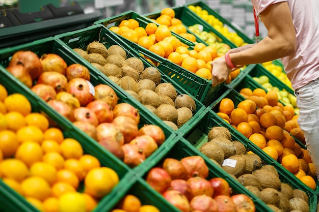 Un commesso mette una scatola di arance su uno scaffale di frutta Diversi frutti sul bancone del mercato