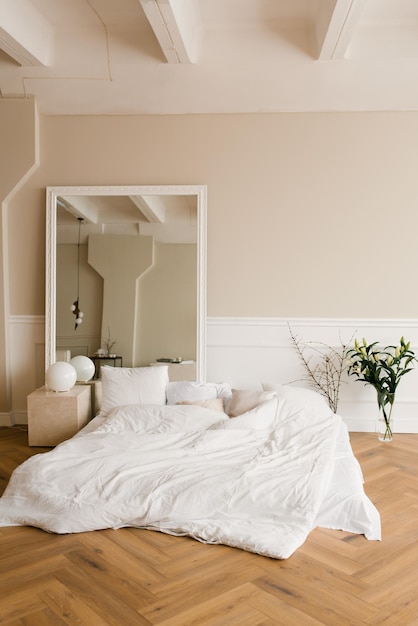 Un comodo letto sul pavimento un grande specchio in una camera da letto classica moderna Interno della casa