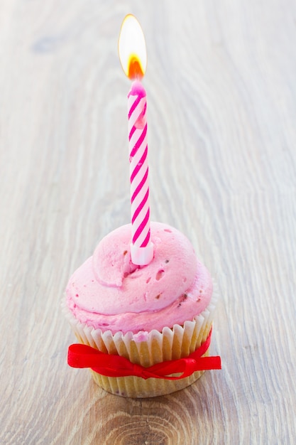 Un compleanno cupcake rosa con candela accesa sul tavolo