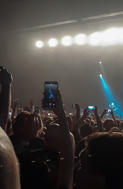 Un concerto rock serale davanti a un vasto pubblico in un club con riprese su un telefono cellulare