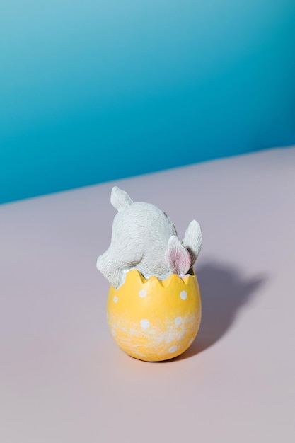 Un coniglio bianco in un uovo di pasqua su sfondo blu il concetto di buona pasqua