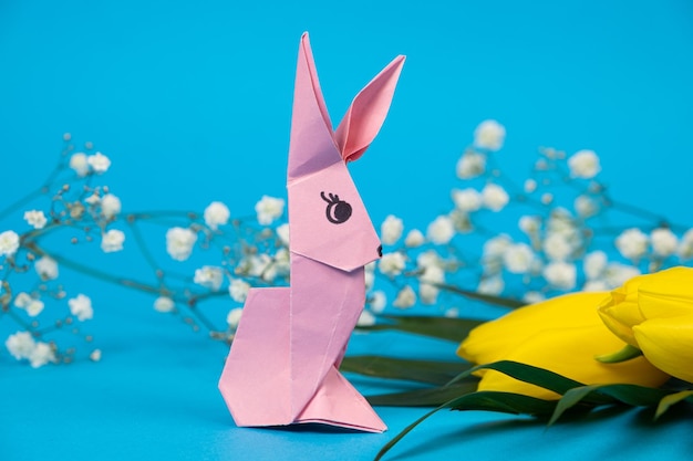 Un coniglio origami rosa su sfondo blu Mestieri per la piega di Pasqua dalla carta fai da te