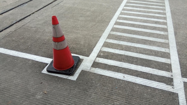 Un cono stradale si trova sulla strada davanti a un passaggio pedonale.