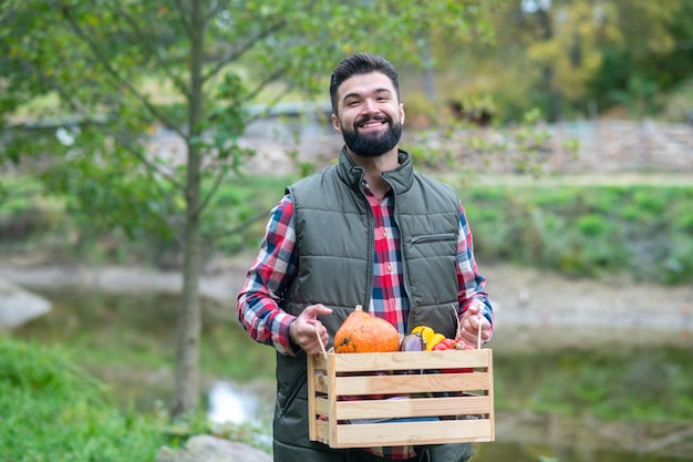 Un contadino maschio che porta una scatola con le verdure