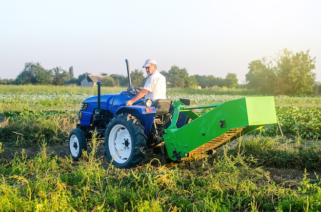 Un contadino su un trattore con un aggregato di attrezzature per scavare patate