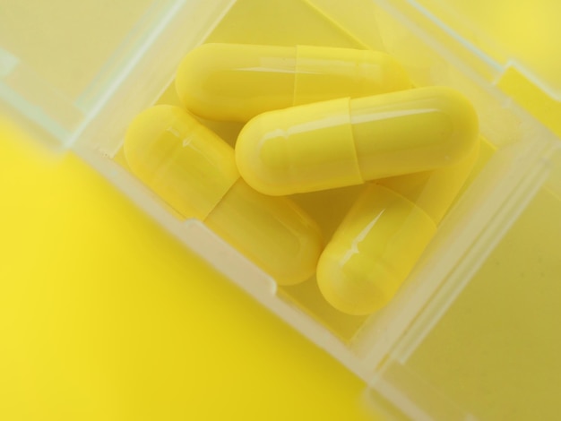 Un contenitore con pillole gialle su sfondo giallo