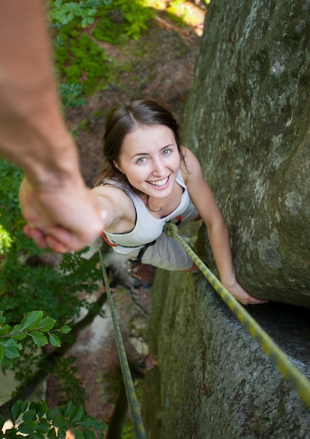 Un coraggioso rockclimber maschio tiene in mano una donna impavida su una parete rocciosa