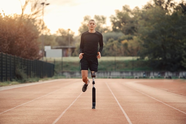 Un corridore disabile con gamba protesica che corre allo stadio sulla pista da corsa