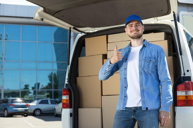 Un corriere felice vicino a un'auto con scatole