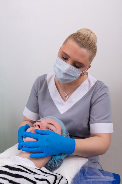 Un cosmetologo femminile tratta manualmente la pelle del paziente con un gel idratante e tonificante