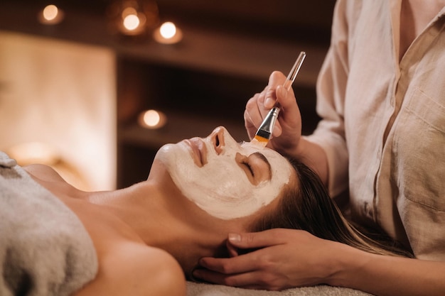 Un cosmetologo realizza una maschera per il viso di una donna per ringiovanire la pelle Cosmetologia