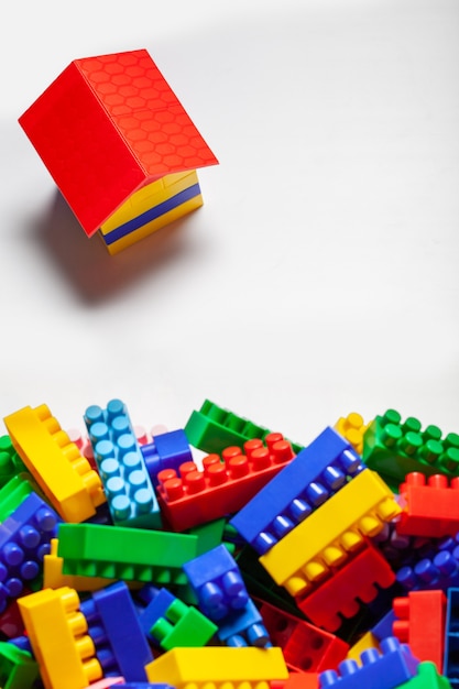 Un costruttore colorato ha impostato il primo piano sulla superficie bianca. Giochi educativi per bambini. cubi di design per bambini in plastica. Il concetto di costruire case, costruire. Vista piana laico e dall'alto