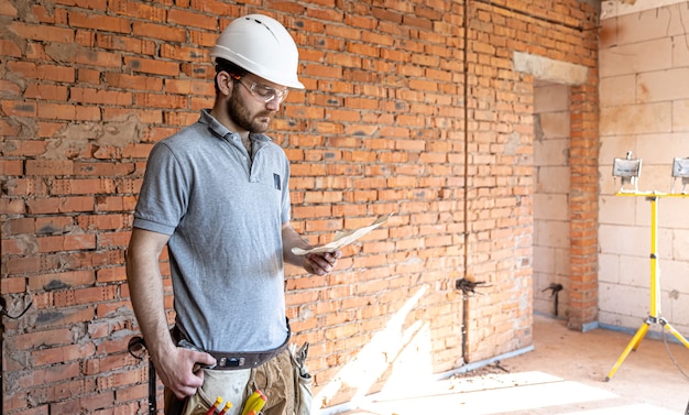 Un costruttore in abiti da lavoro esamina un disegno di costruzione in un cantiere.