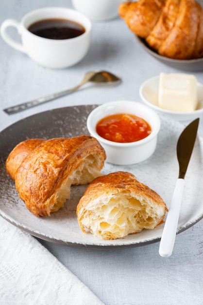 Un croissant francese al caffè appena sfornato, burro e marmellata