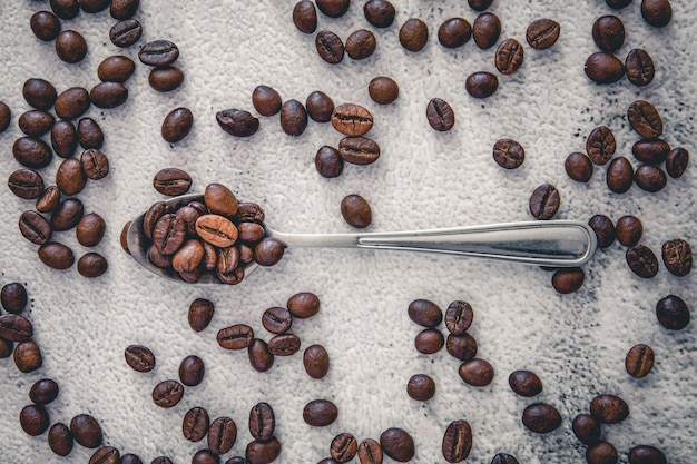 Un cucchiaio d'acciaio su uno sfondo di chicchi di caffè sparsi