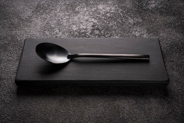 Un cucchiaio da tavola nero su un podio di legno. elegante natura morta minimalista.