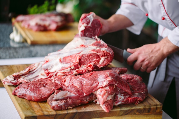 Un cuoco uomo taglia la carne con un coltello in un ristorante.