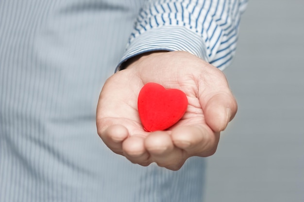 Un cuore in mani umane su sfondo bianco mattone