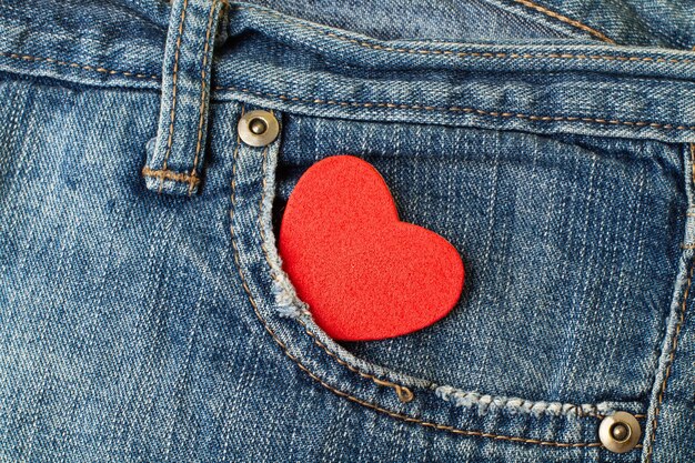 Un cuore rosso nella tasca di un pantalone jeans blu in vista ravvicinata