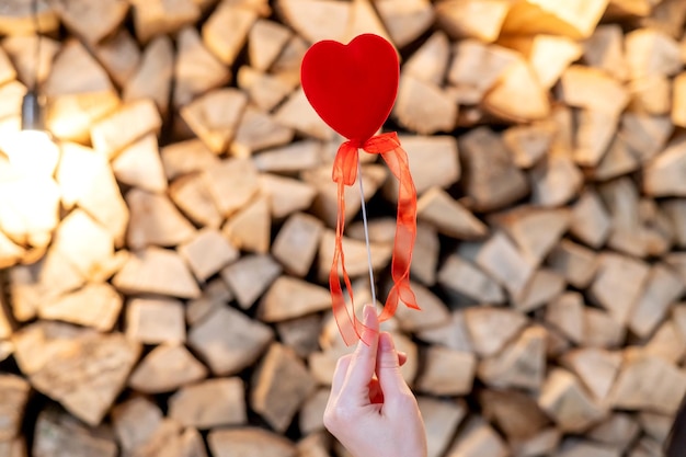 Un cuore rosso su un bastone è tenuto dalla mano di una donna