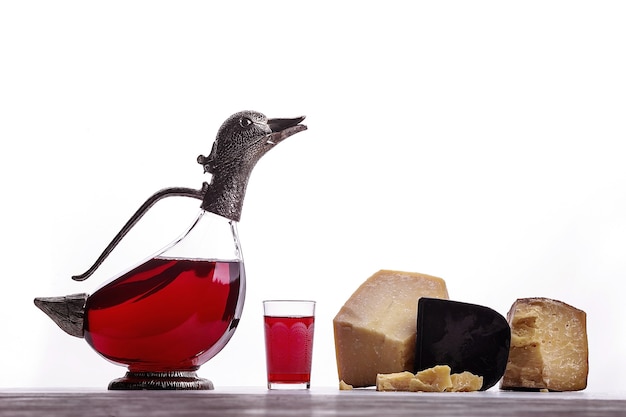 Un decanter di vino rosso, un bicchiere di vino, formaggi costosi, formaggio con muffa, formaggio nero. Su sfondo bianco. Posto per il logo.